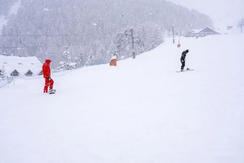 Professional instructor is teaching a boy to ride a snowboard on a mountain Stock Photos