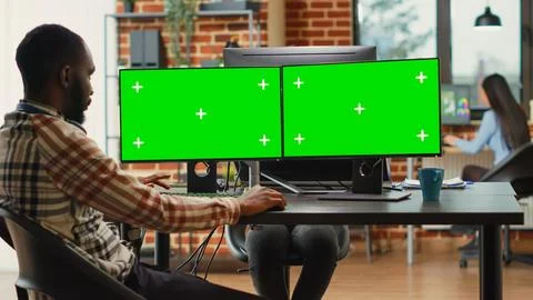 Professional IT expert analyzing greenscreen on multiple monitors Foto stock