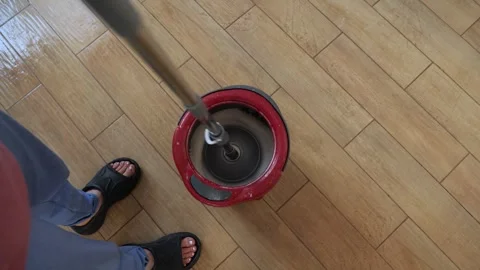 Professional janitor squeezing wet mop into red bucket, cleaning wooden hardwood Vidéo 305276013