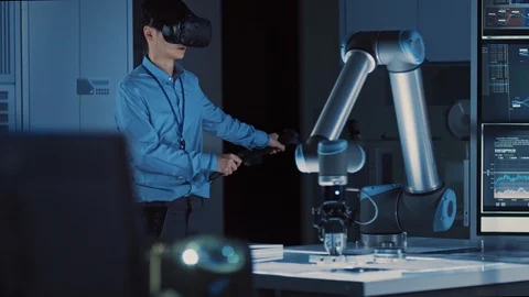 Professional Japanese Development Engineer in Blue Shirt is Controlling Robot Stock Footage 105353415