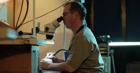 Professional jeweler drilling ring while looking through microscope Stock Footage 265659942
