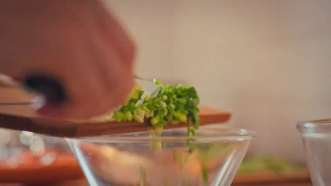 In professional kitchen chef pours chopped fresh herbs into a clear bowl ass Stock Footage 332481029