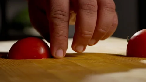 In a professional kitchen, a chef slices a tomato on a cutting surface before Stock Footage 232778629