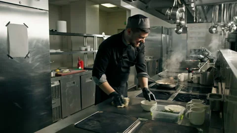 Professional kitchen in a hotel restaurant the chef wipes the stove with a Stock Footage 237889040