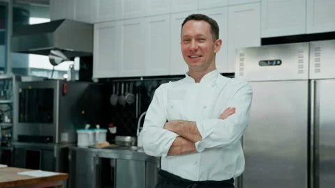 Professional kitchen smiling and satisfied chef in white coat standing with Stock Footage 237919910