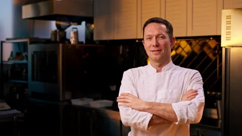Professional kitchen smiling and satisfied chef in white coat standing with Stock Footage 273562326