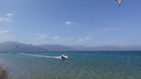 Professional kitesurfer performing tricks beside a Greek island beach Stock Footage 337046331