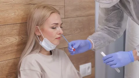 Professional laboratory assistant in protective suit takes swab from nose of Stock Footage 150558670