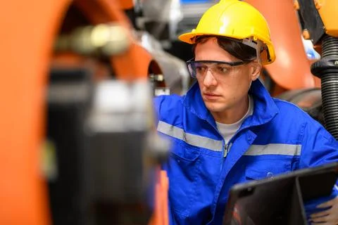 Professional maintenance worker with machine robotic arms at industrial factory Stock Photos