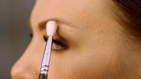 Professional make-up artist applying eyeshadow on the eyelid on her face. 4K Stock-Footage 79856853