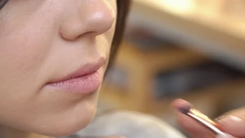 Professional make-up artist applying lipstick on lips of client in beauty salon Stock Footage