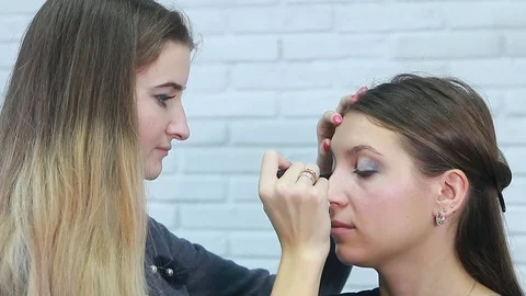 Professional make-up artist applying mascara on eyelashes of model in white room Stock Footage 81903549