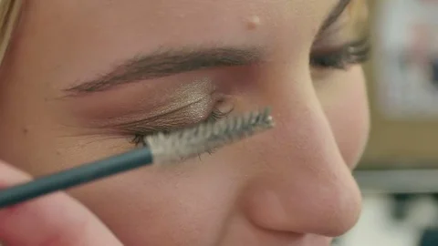Professional make-up artist combing eyelashes of model Stock Footage 74640993