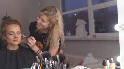 The professional make-up artist does make-up for the young cute model. two Stock-Footage 83756837