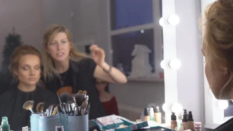 The professional make-up artist does make-up for the young cute model. two Stock Footage 83757571