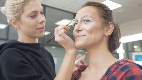 A professional make-up artist does the make-up of the model. Video stock 84987449