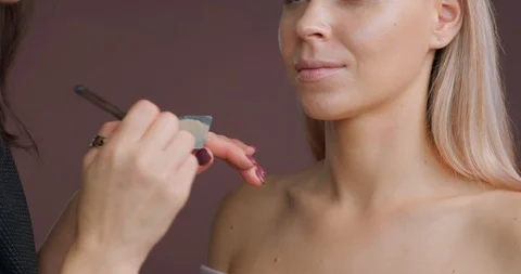 Professional make-up artist does makeup of model, applies foundation brush Stock Footage 120149124