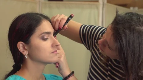 Professional make-up artist doing make-up for beutiful model. Gentle make-up for Stock Footage 72110398
