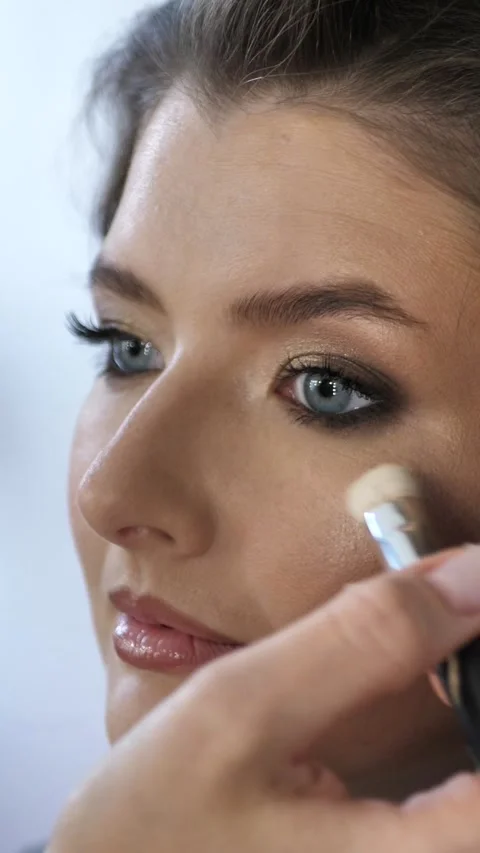 Professional make-up artist doing make-up to a young woman in a beauty salon Stock Footage 299624227
