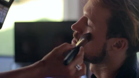 Professional make up artist is doing young man make up in studio. Stock-Footage 85524623
