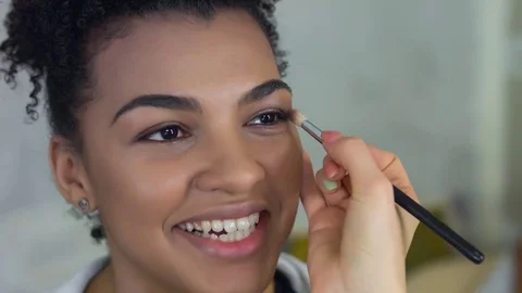 Professional make-up artist makes makeup of afro-american model. Beauty and Stock Footage 75371249
