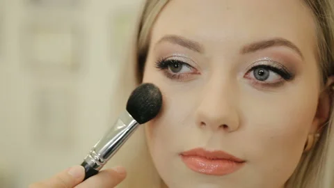 Professional make up artist using brush to paint cheeks of luxurious models face Stock Footage 131335022
