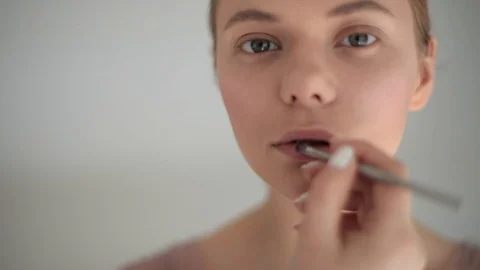 Professional make-up artist working with model applying lip gloss with brush Stock Footage 93759565