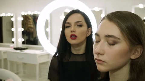 Professional make-up artists making pretty girl's face up at master-class. HD Stock Footage 72868634