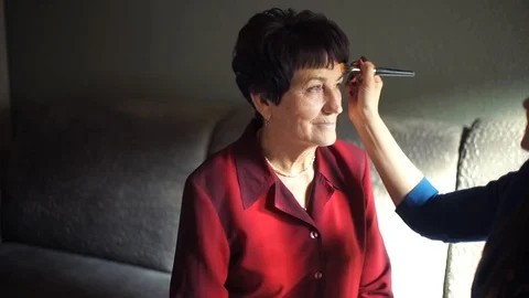 Professional make-up. Makeup artist doing makeup for an elderly woman Stock Footage 106377918