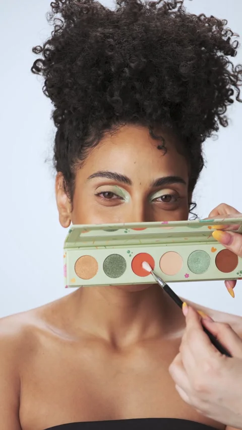 Professional make-up master applies paint to a young model with curly hair Stock Footage 310427707