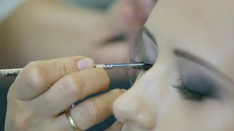 Professional makeup artist applying eye pencil and brush for eyelid arrows. Stock Footage 78012003