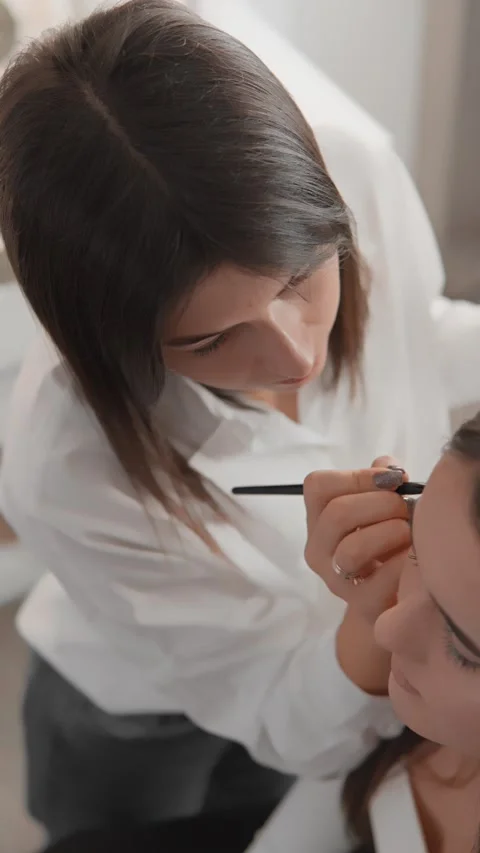 Professional makeup artist applying flawless makeup to a client in a modern Stock Footage 340921911