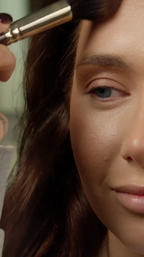 Professional makeup artist applying soft blush, highlighting models cheekbones Stock Footage 304338776