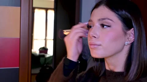 Professional makeup artist carefully applying powder blush on a client's Stock Footage 326009758