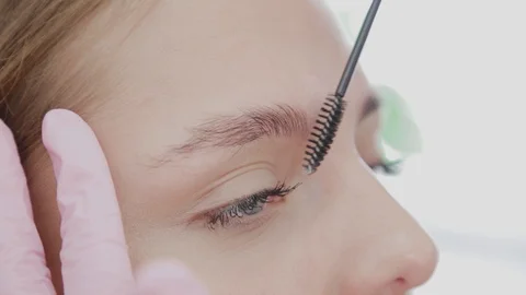 Professional makeup artist combing eyebrows with a special eyebrow brush of a Video stock 117314065