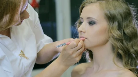 Professional makeup artist makes makeup young woman lips with lip pencil. Stock Footage 78157376