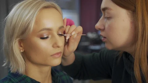 Professional makeup artist making eye-makeup for young model Stock Footage 101025178