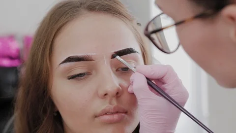 Professional makeup artist paints eyebrows to client with henna. 库存影片 117315504