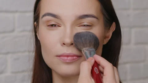 Professional Makeup Artist Using Large Fluffy Brush to Remove Excess Powder from Stock Footage 327789402