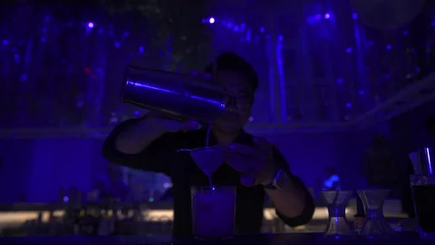 Professional Male Bartender Double Straining Cocktail Under Blue Bar Lighting 4K Vídeos de archivo 329225978