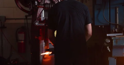 Professional male blacksmith walking into workshop and pressing piece of metal w Stock Footage 199462468