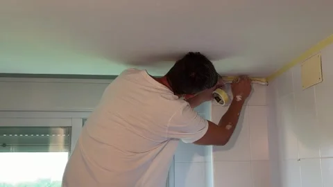 Professional male painter applying masking tape to a wall for renovation Stock Footage 341362909