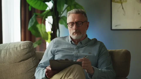 Professional male psychologist taking notes about patient after therapy session Stock Footage 332985412