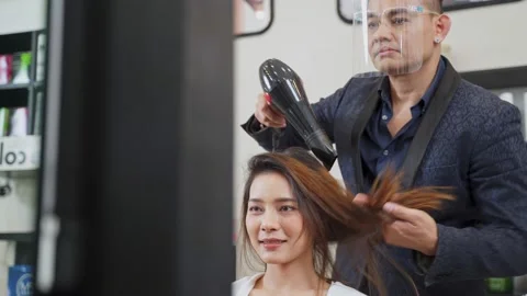 Professional male stylist using hair dryer blow woman's hair in salon. Stock Footage