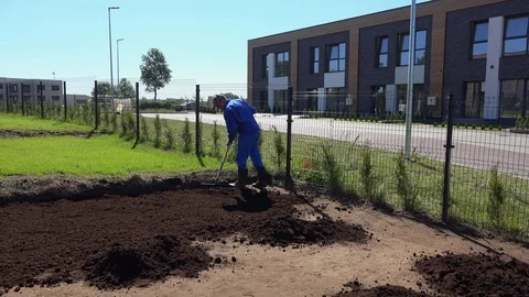 Professional male worker with rake tool leveling soil compost. Static shot. Stock Footage 129539688
