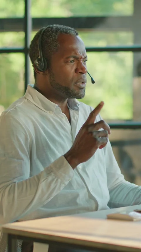 A professional man with a headset is diligently working at his desk in a modern Stock Footage 314361829