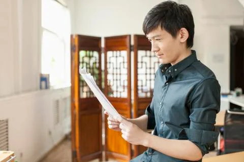 Professional Man Looking at Papers in Office Stock Photos