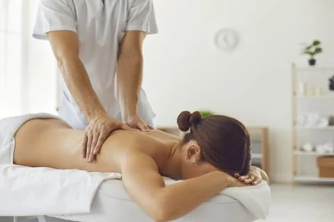 Professional man masseur making manual relaxing back massage to relaxing woman Stock Photos