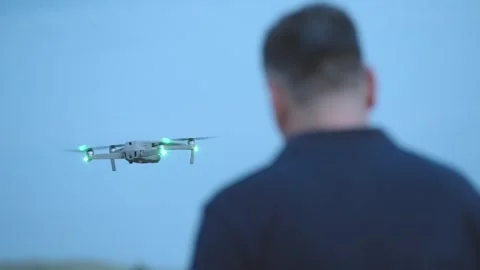 Professional man pilot operating a drone with remote control against blue hou Stock Footage 330121518