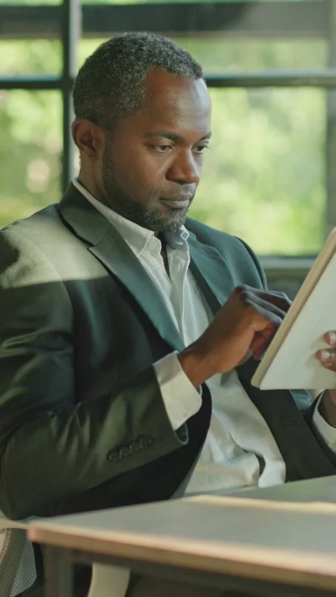 A professional man reads in a modern office, showcasing calm, creativity Stock Footage 314362665